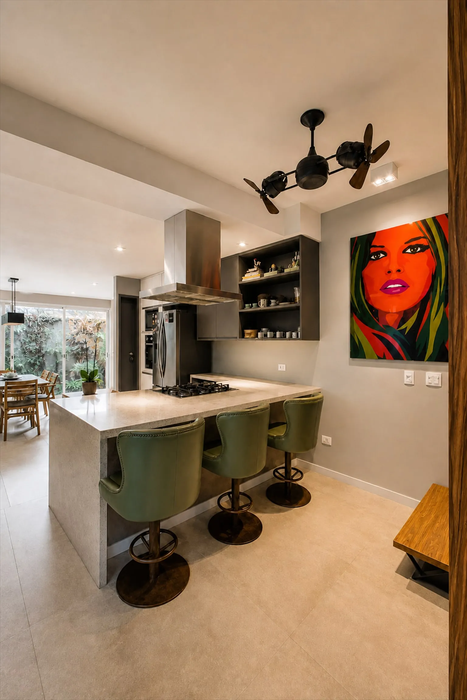 Cozinha com ilha central, cooktop, coifa de inox e três banquetas verdes