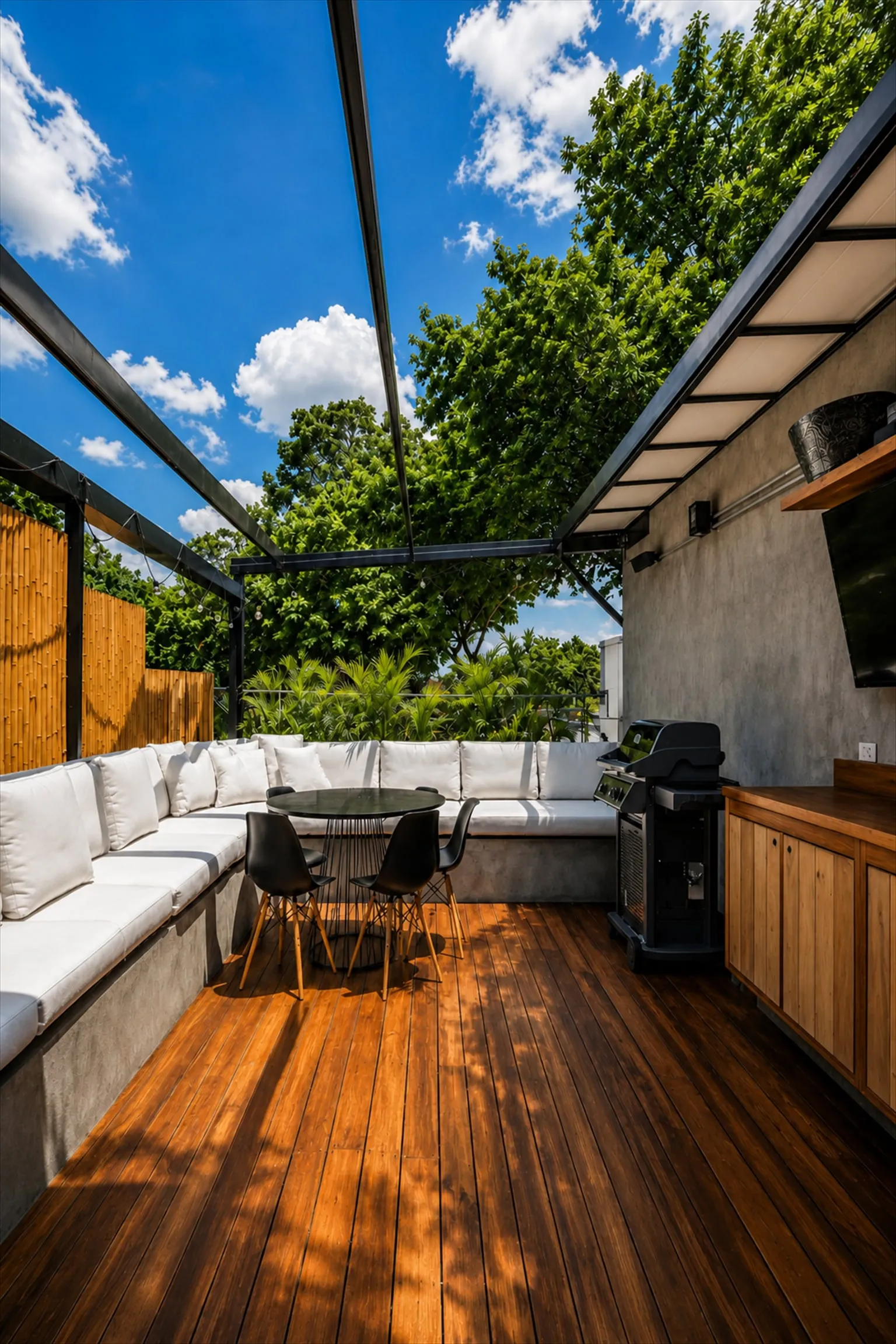 Área coberta do rooftop com sofá em L branco, mesa redonda e churrasqueira a gás
